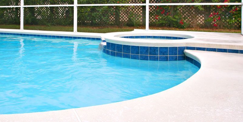 Pool with blue water and adjacent hot tub, bordered by white concrete and blue tiles.