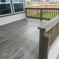 Gray wooden deck with a wooden railing.