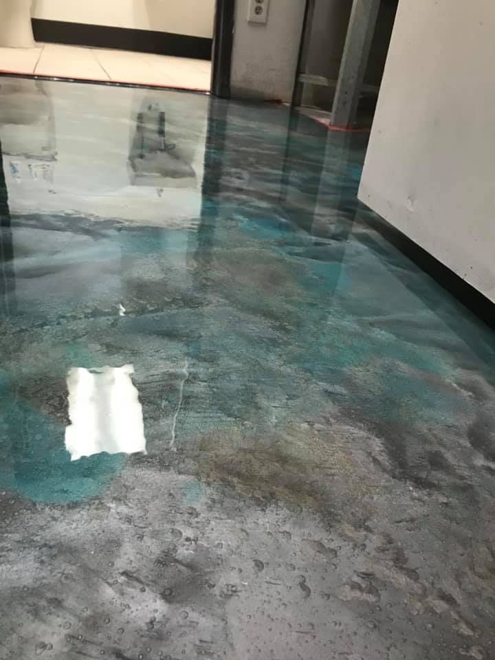Metallic epoxy floor with shades of blue, gray, and silver. Reflective surface in a hallway.