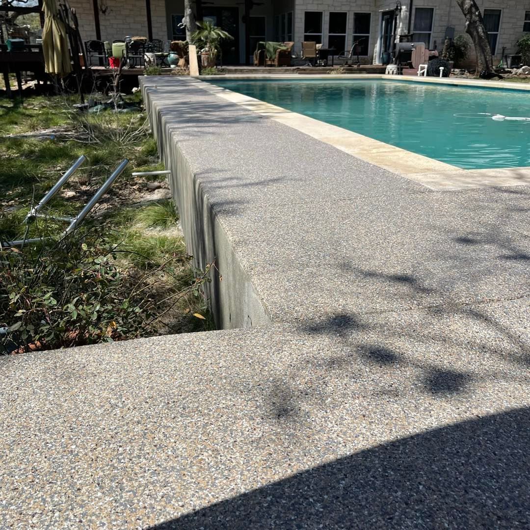 Concrete pool deck and steps leading to a turquoise swimming pool in a backyard.