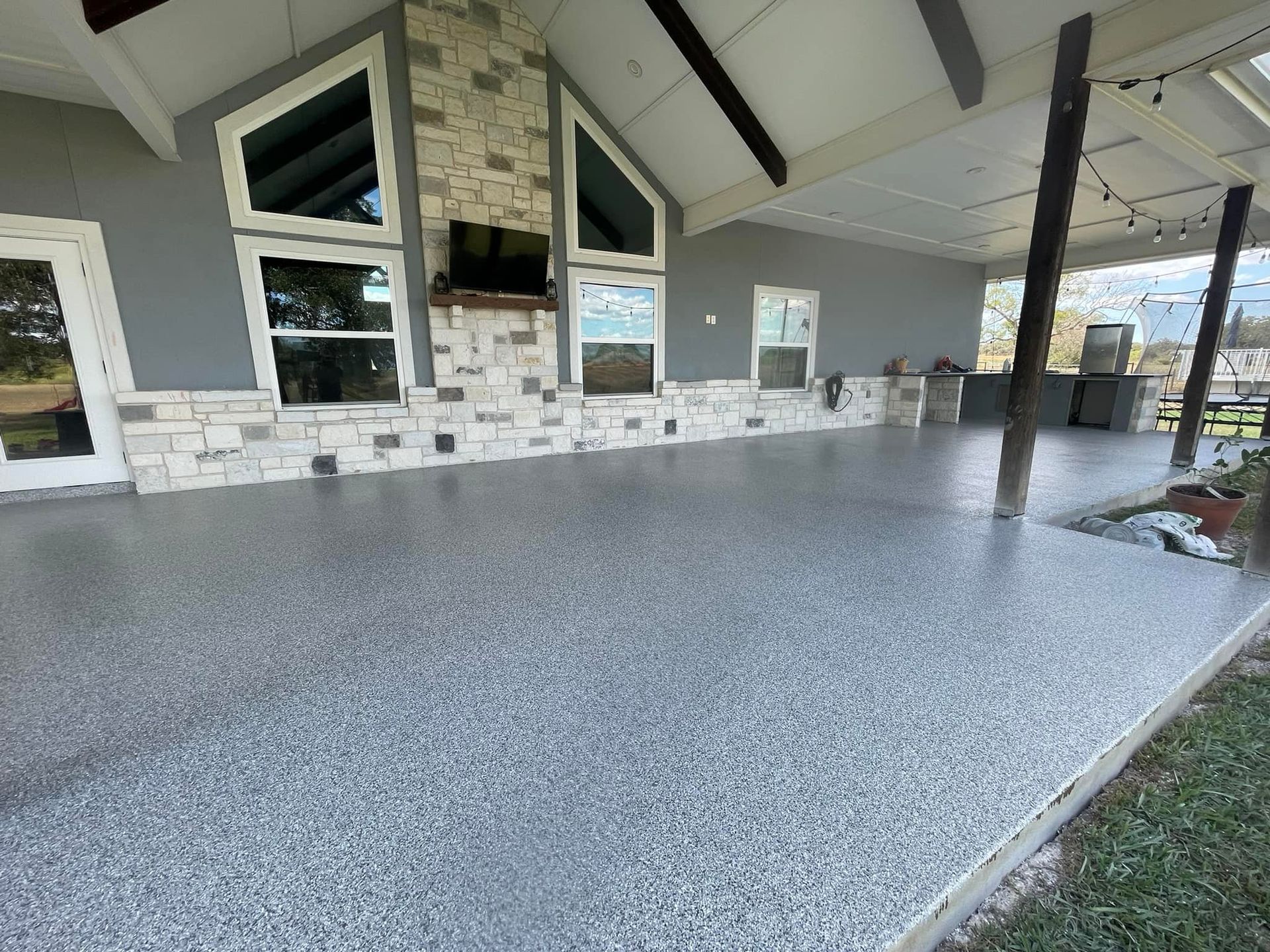 Grey epoxy-coated patio with fireplace and windows.