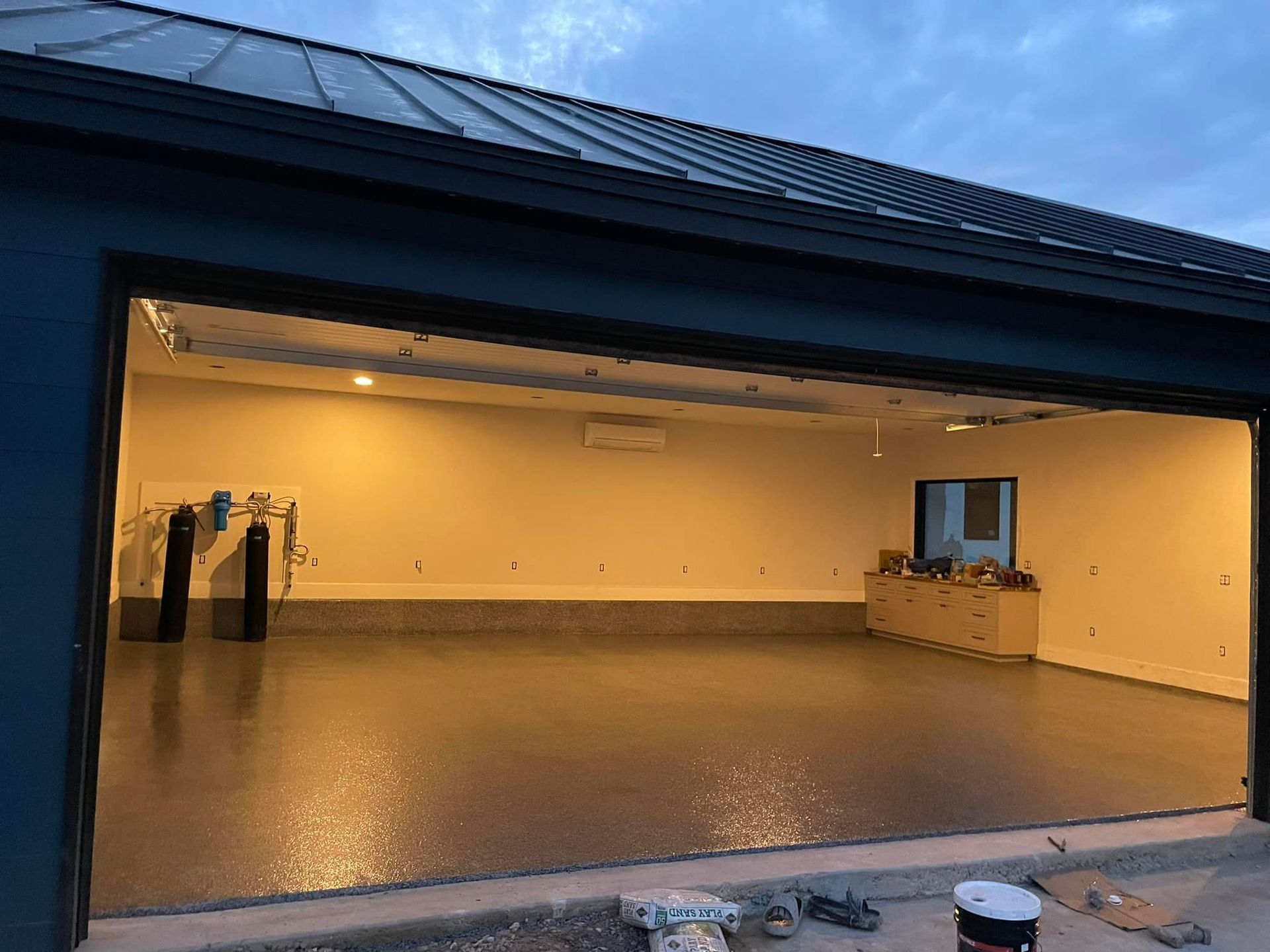 Open garage with shiny epoxy floor, tan walls, and dark blue exterior.