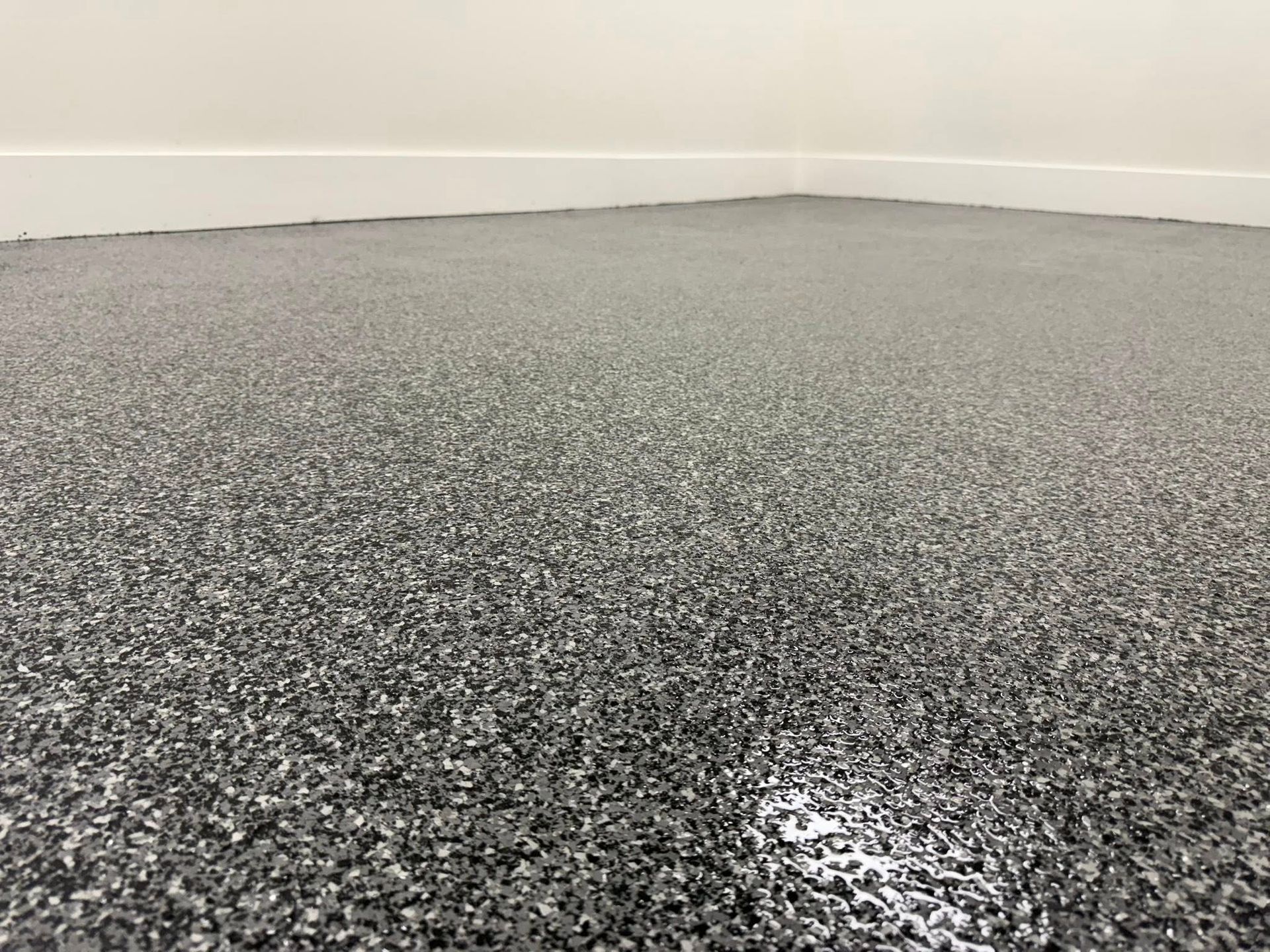 Gray speckled epoxy floor with white baseboard.
