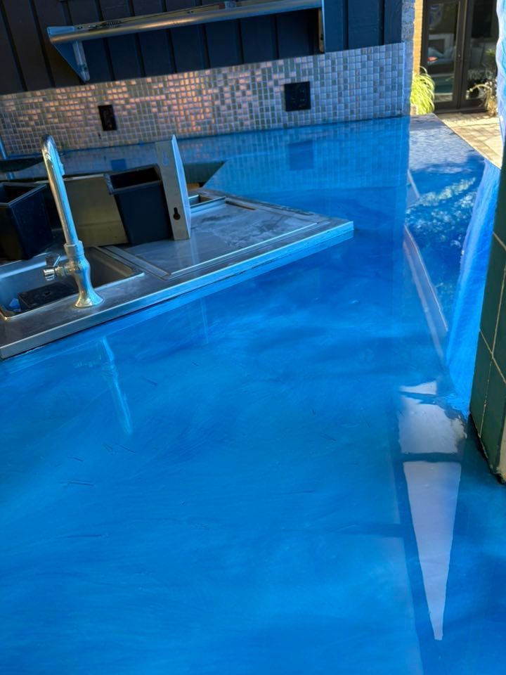 Blue epoxy countertop, reflective surface, stainless steel fixtures, indoor setting.