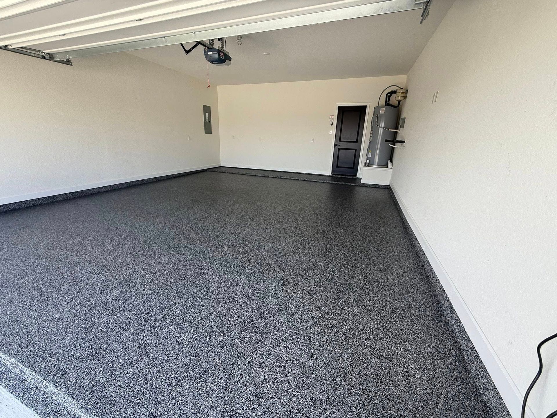 Empty garage with a speckled dark gray epoxy floor and white walls.