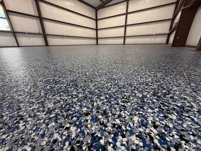 Blue, gray, and white speckled epoxy floor inside a metal-framed building.