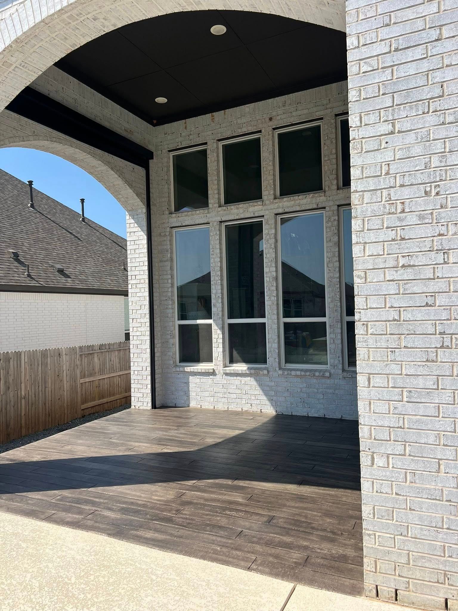 Covered patio with brick walls, tall windows, and a dark ceiling.