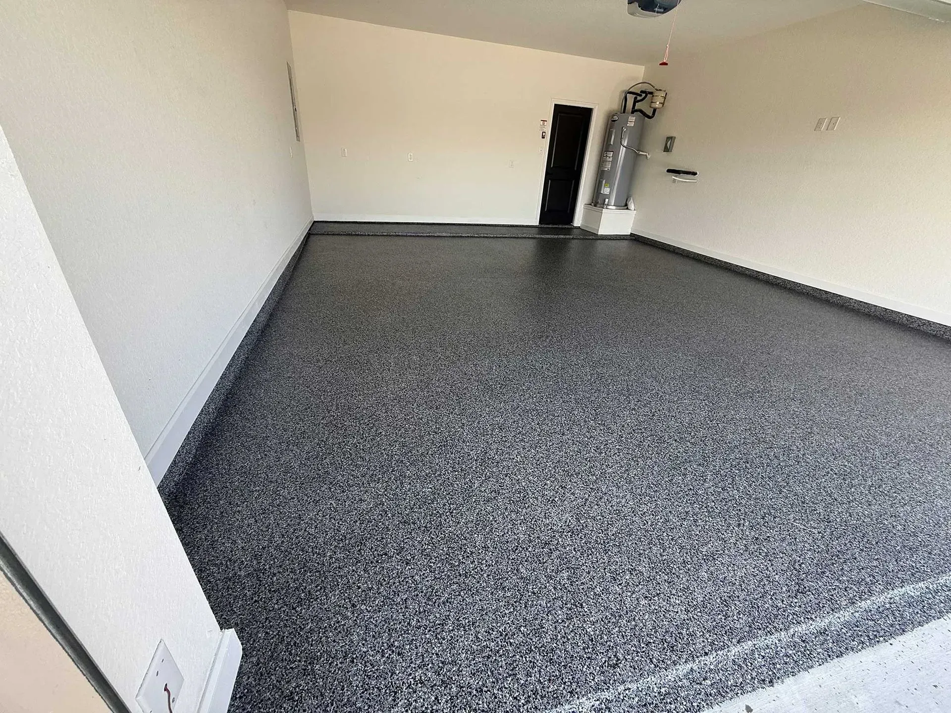 Empty garage with a dark speckled epoxy floor and light walls.