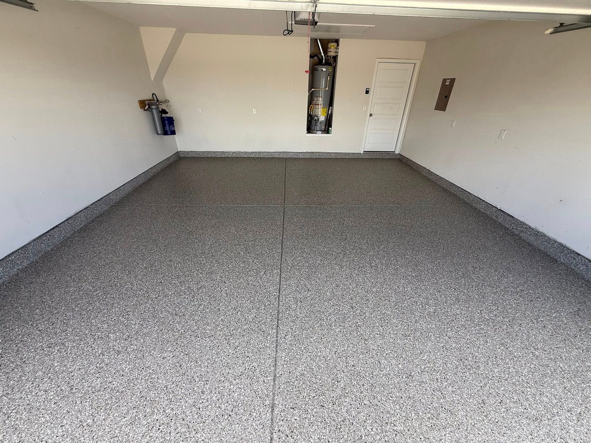 Empty garage with gray speckled epoxy floor and white walls.