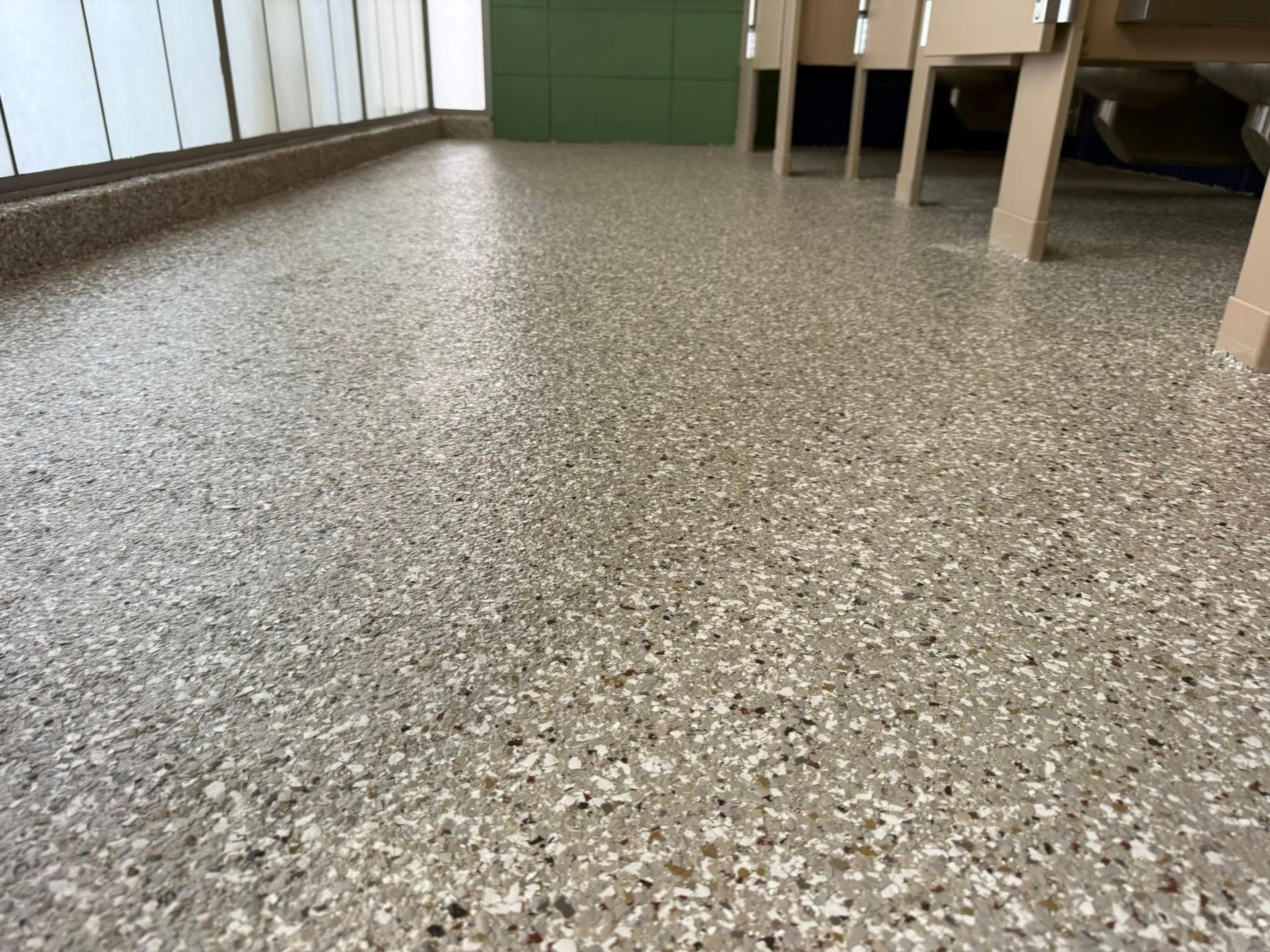 Terrazzo-style flooring with flecks of various colors in a room with light and neutral walls.