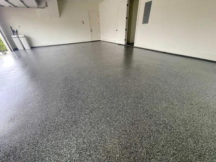 Garage with a speckled, glossy concrete floor. Walls are white.