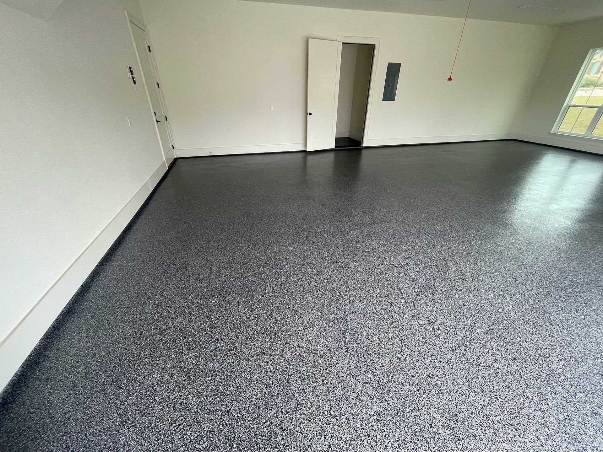 Garage with dark speckled epoxy floor and white walls.