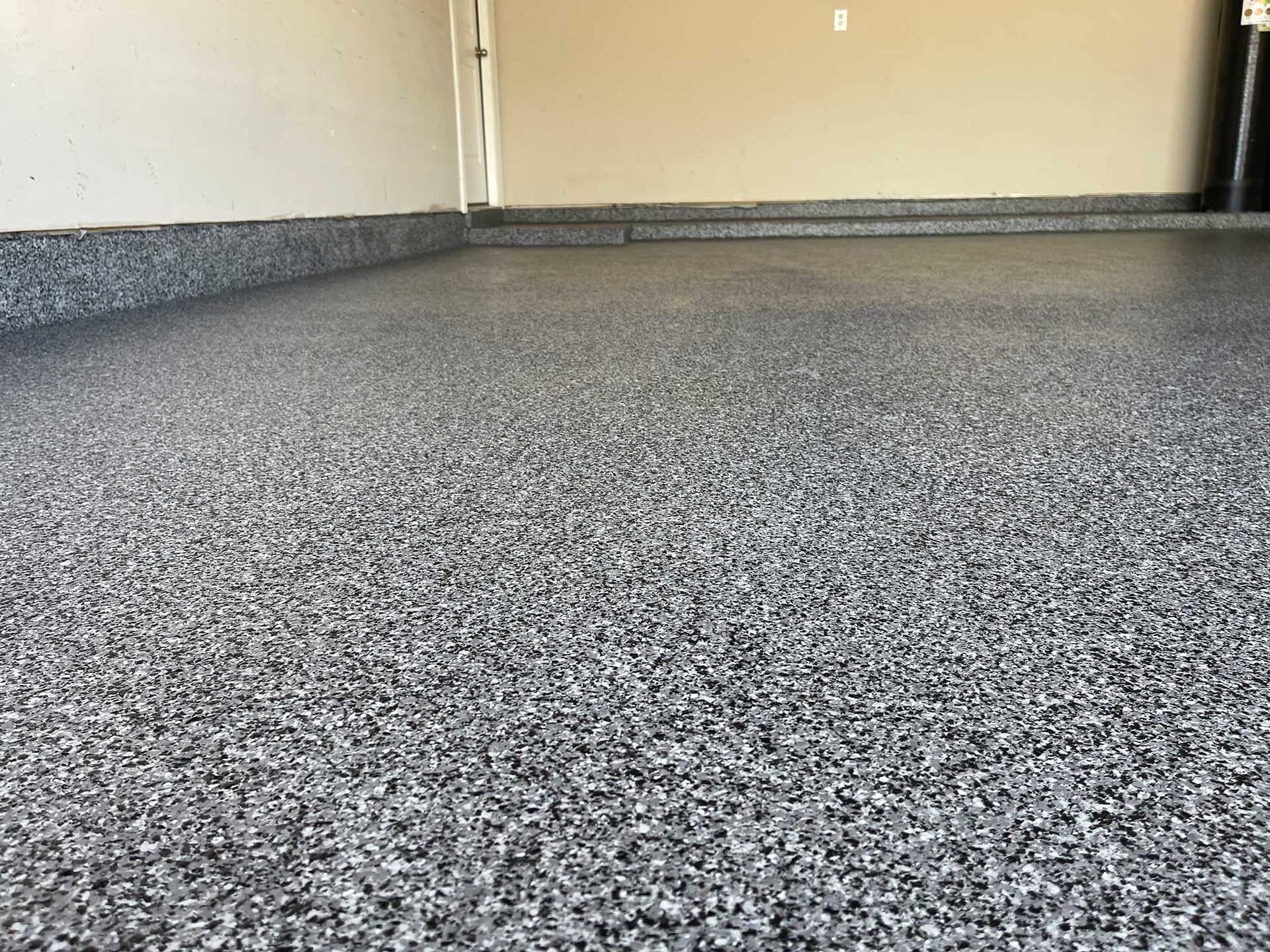 Garage floor with a speckled, gray epoxy coating.