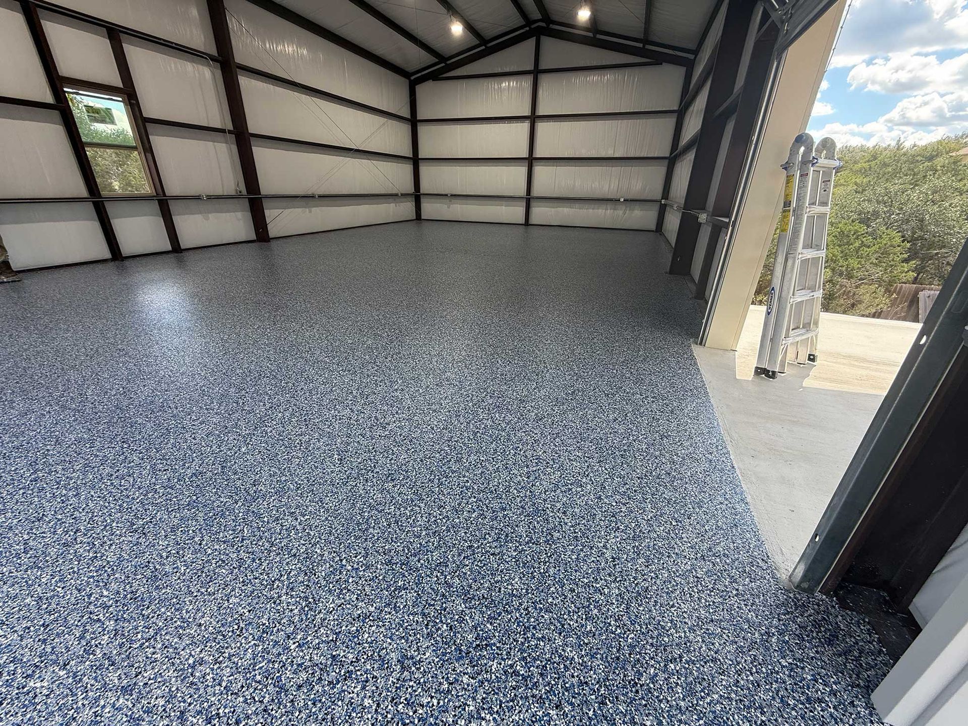 Interior of a newly constructed metal building with a speckled epoxy floor.