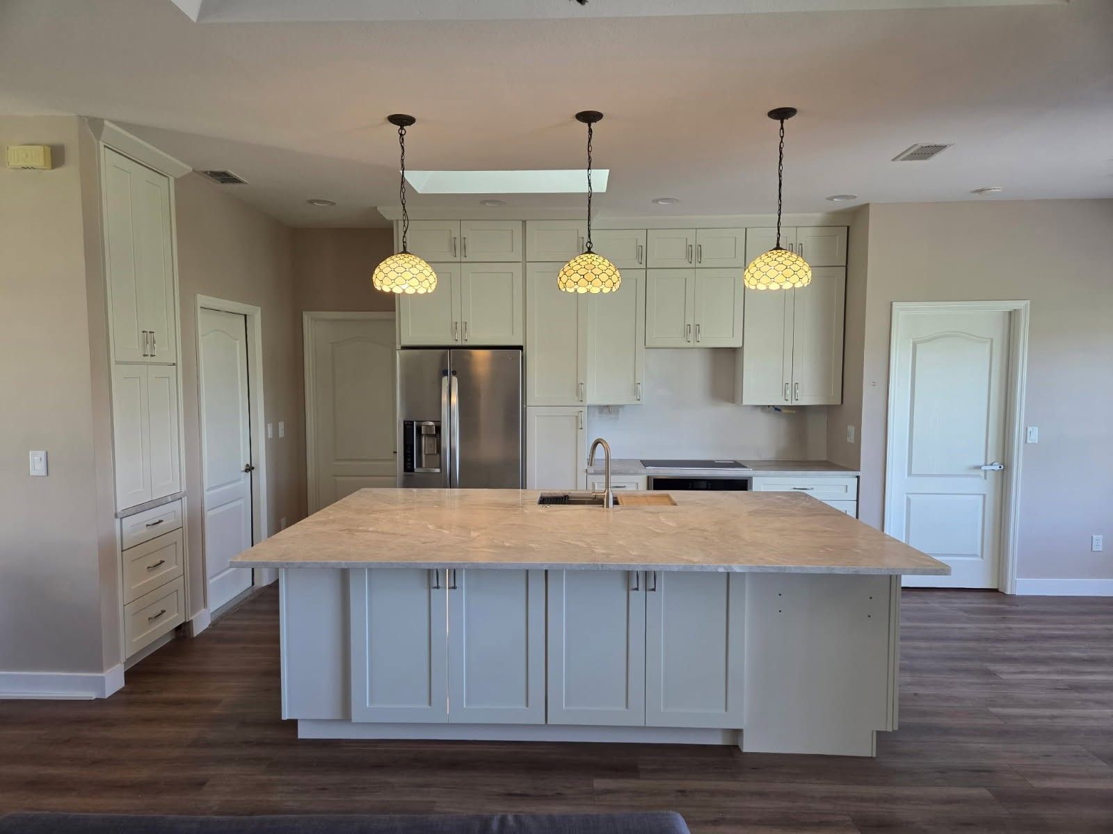 Bright kitchen with large island, white cabinets, pendant lights, and stainless steel appliances