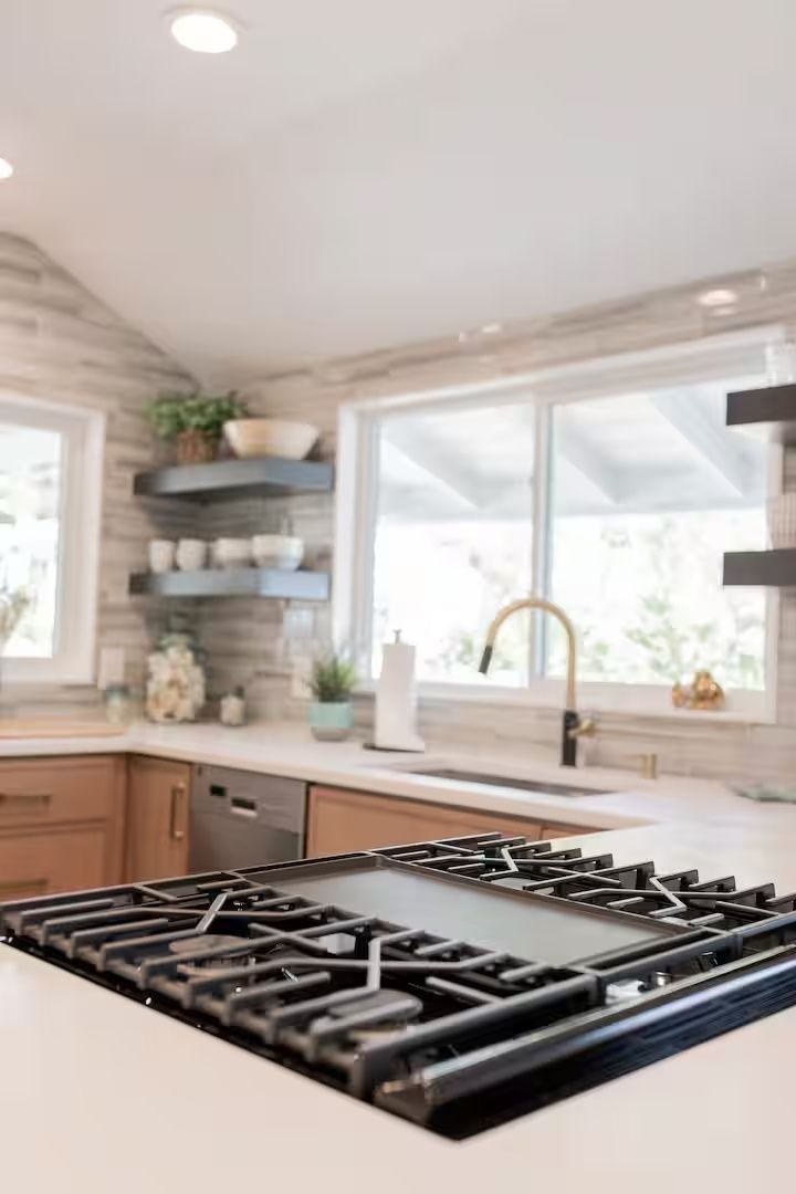 Modern kitchen with a gas stovetop, white countertops, and large windows above the sink