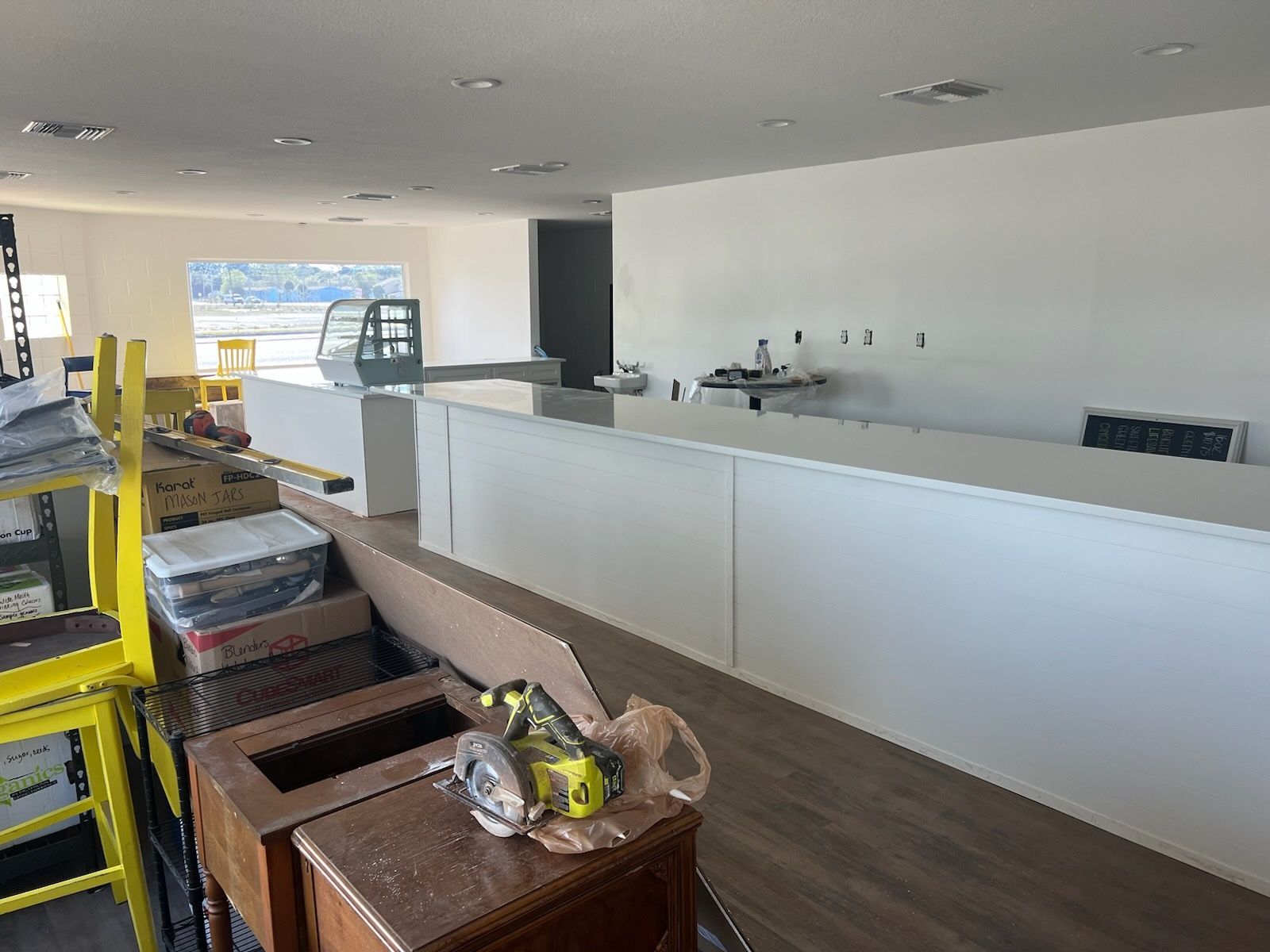 Empty modern kitchen with white island, dark wood floor, and yellow ladder on the left