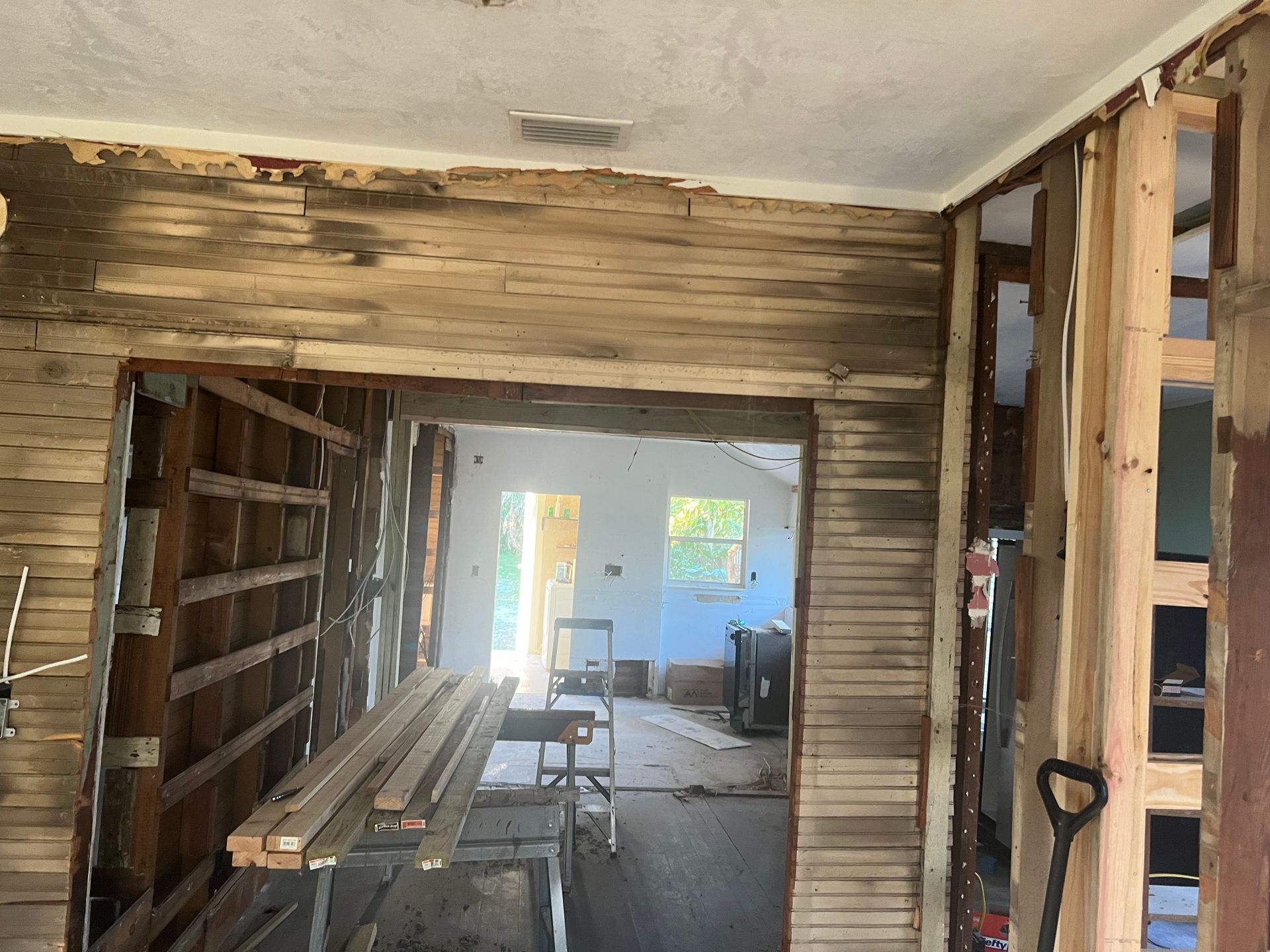 Partially renovated hallway with exposed wood framing, drywall, and construction tools inside a house
