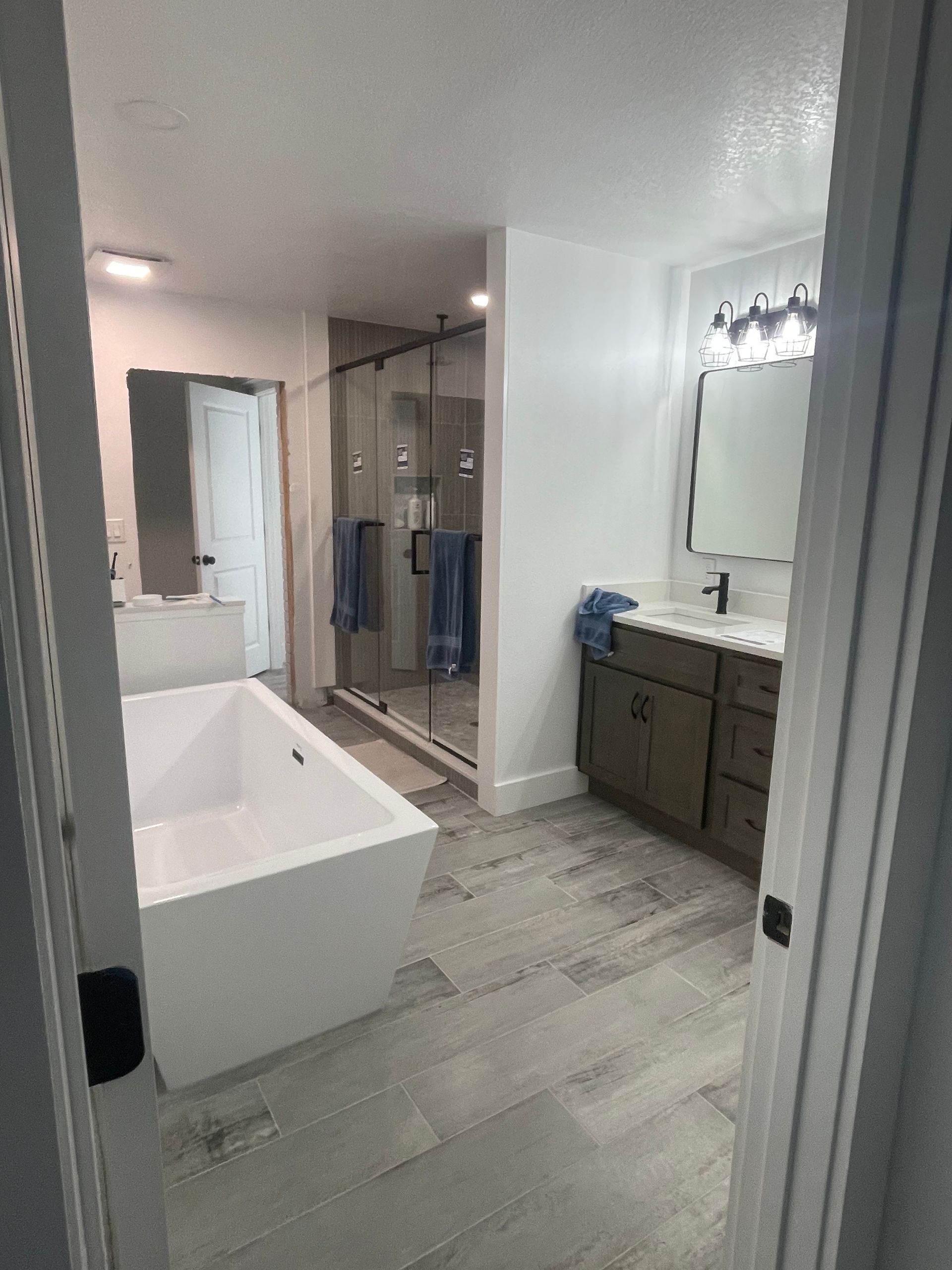 Modern bathroom with freestanding tub, glass shower, vanity, and light tile floor