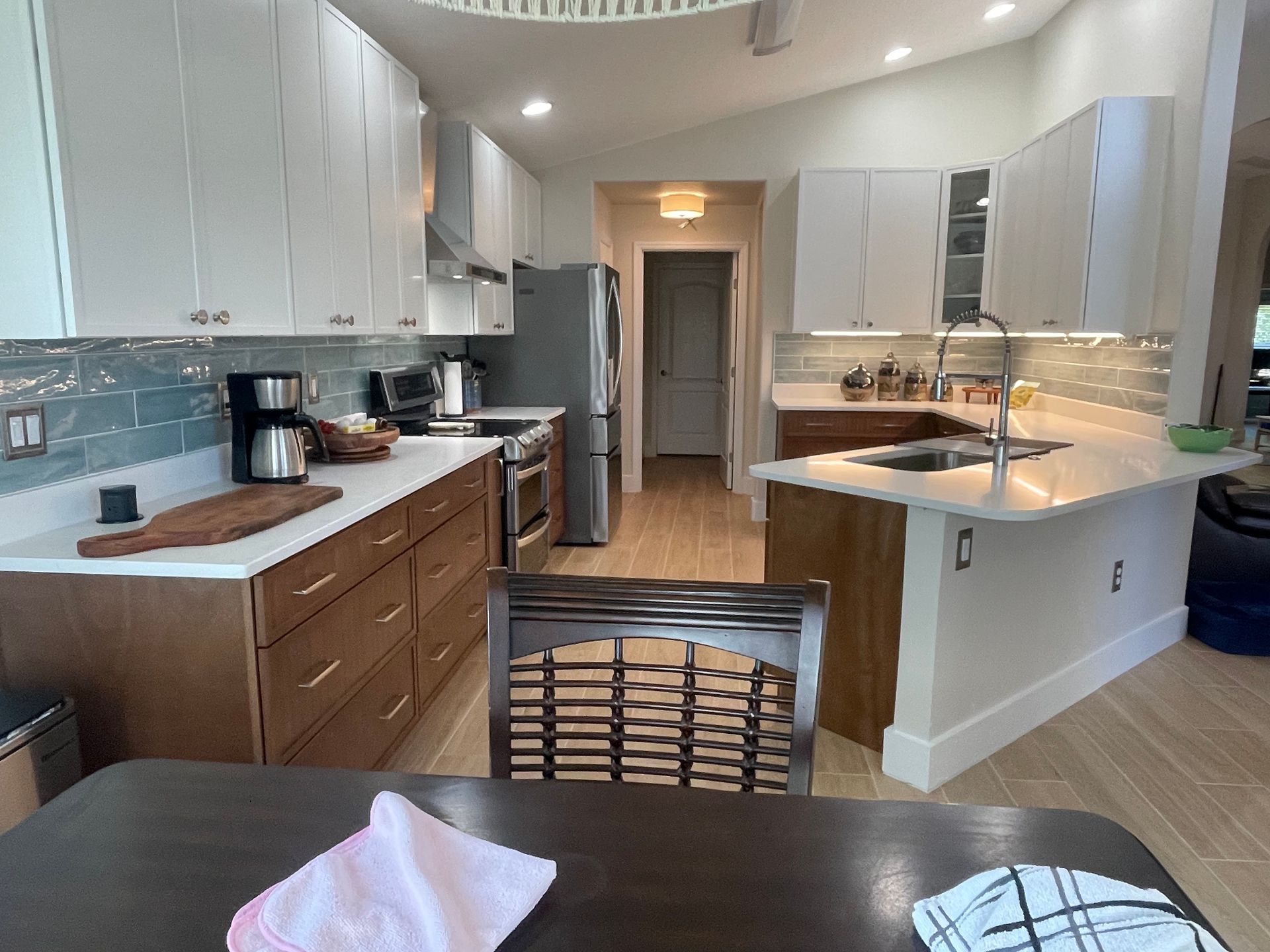 Bright modern kitchen with white cabinets, wood counters, and a center island with sink.