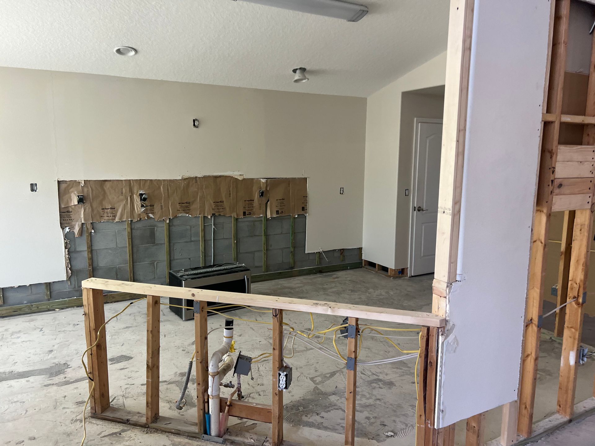 Renovated room with exposed framing, drywall, and debris on the floor