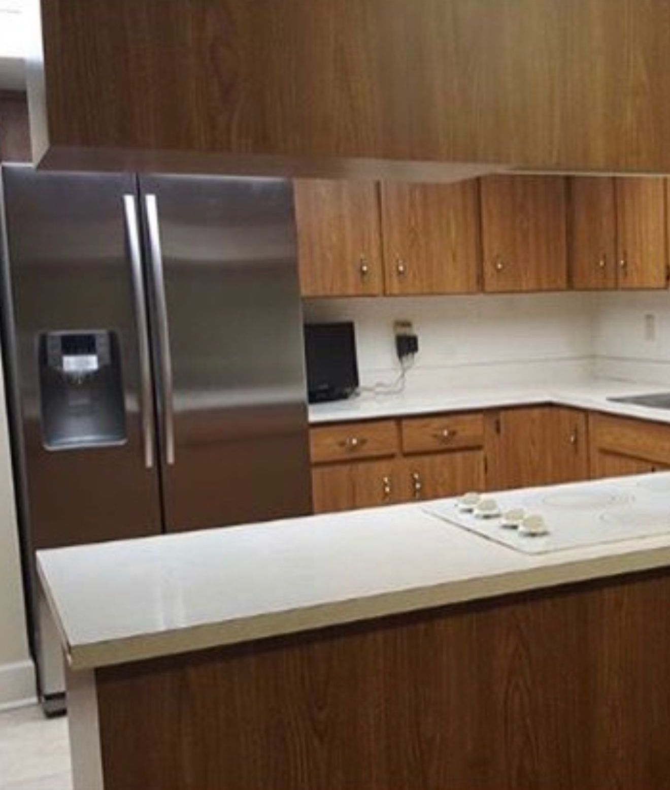 Modern kitchen with stainless steel fridge, wood cabinets, and a white island countertop