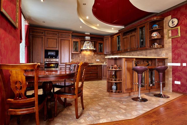 Luxurious home bar and kitchen with dark wood cabinetry, red walls, and marble flooring