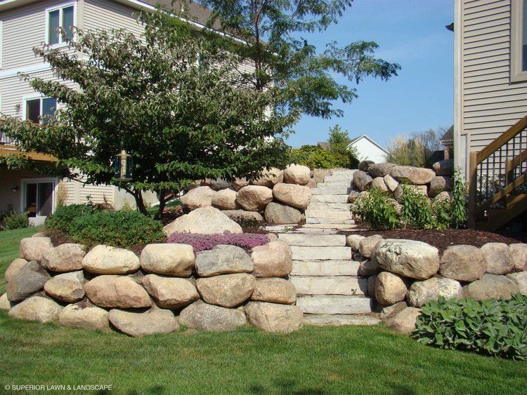 A stone wall with stairs leading up to a house
