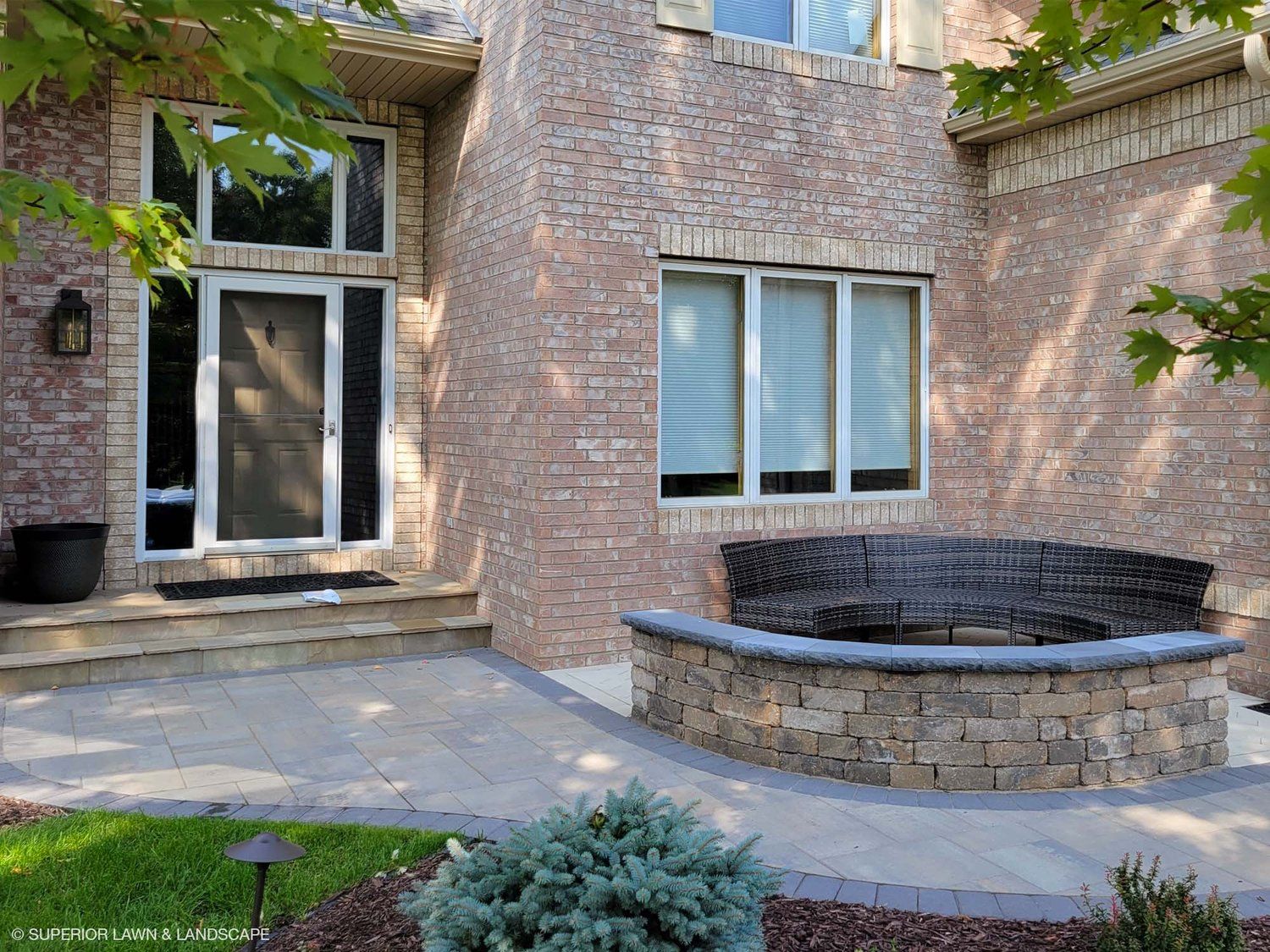 A brick house with a patio and a fire pit in front of it.