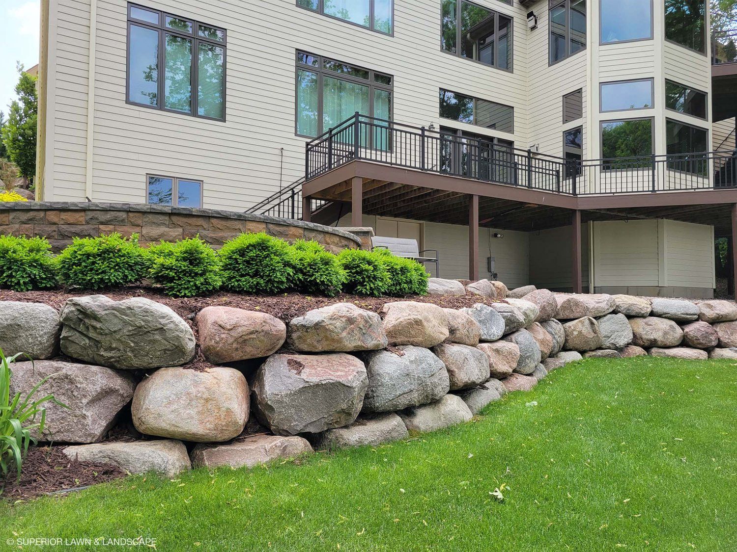 A large house with a large rock wall in front of it.