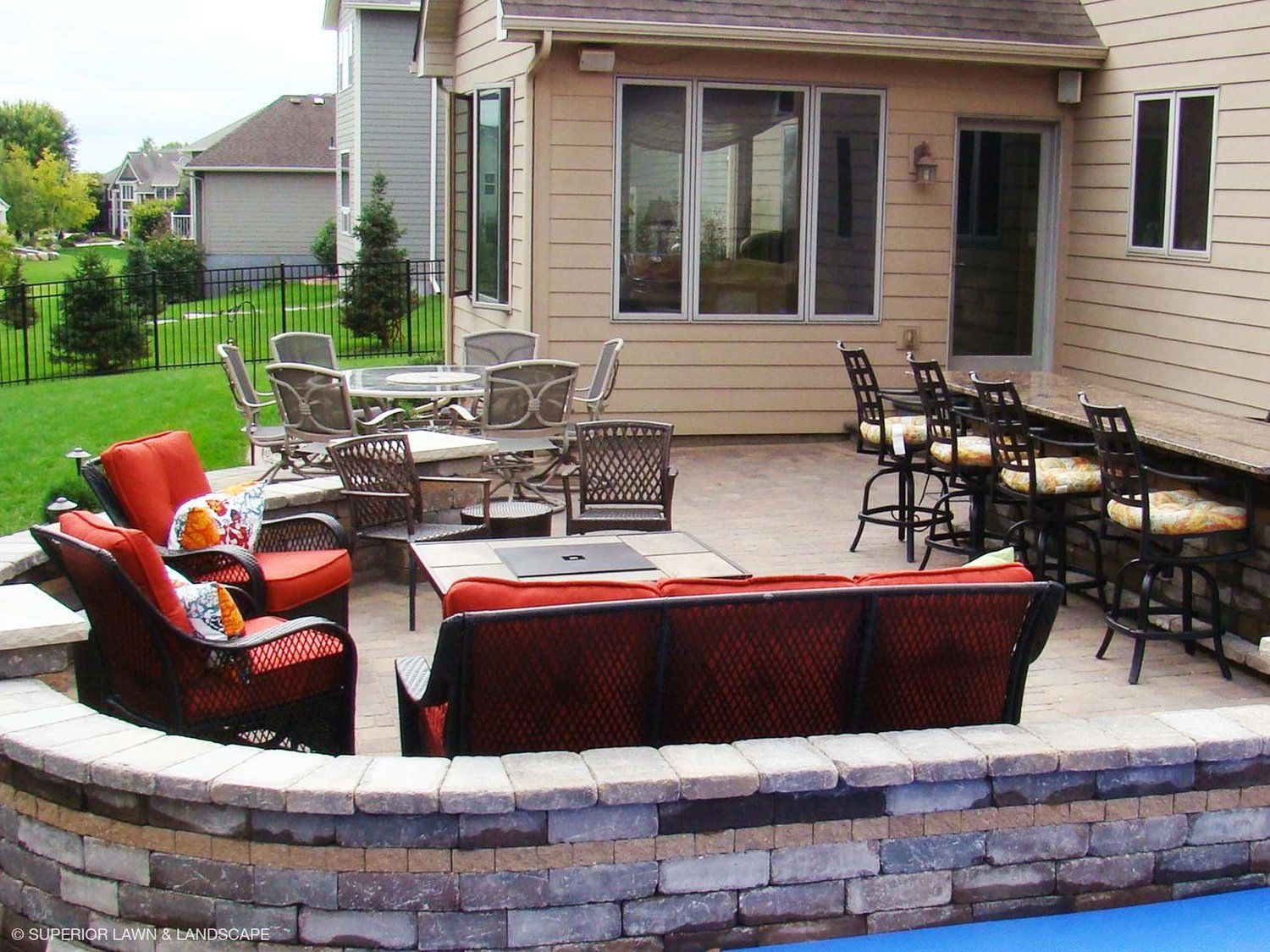 A patio with a couch and chairs in front of a house