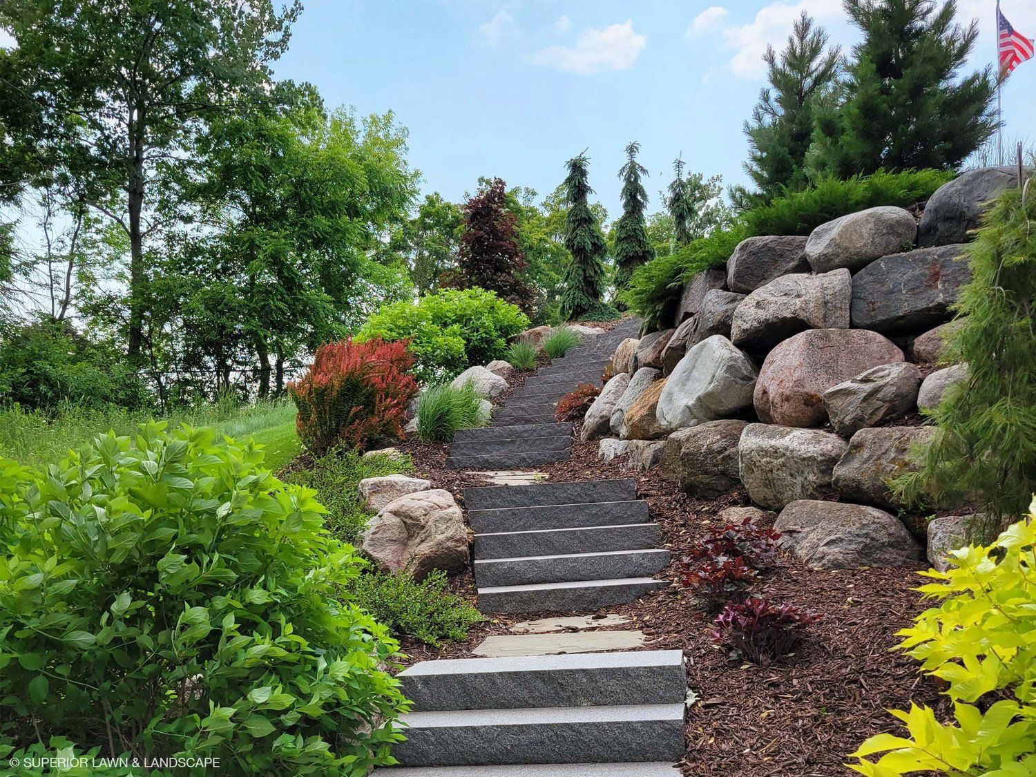 A set of stairs leading up to a rock wall in a garden.