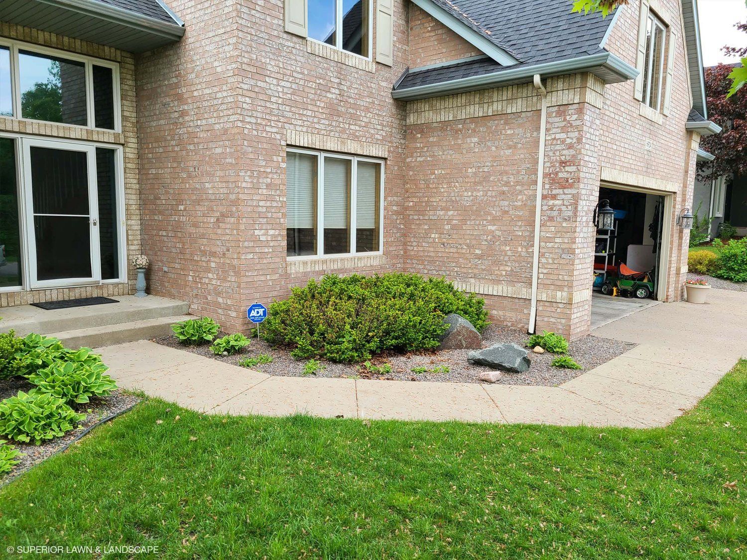 A brick house with a walkway leading to it and a garage.