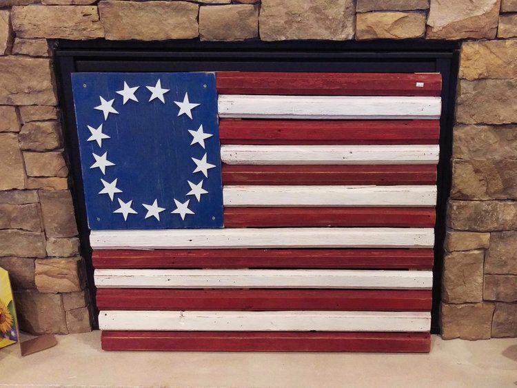 A wooden american flag is hanging on a stone wall