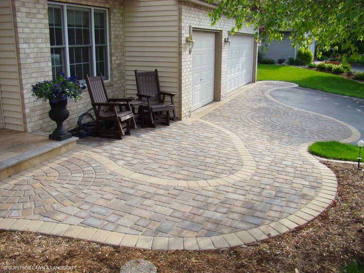 Two rocking chairs are sitting on a patio in front of a house.