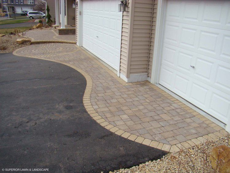 A driveway with a brick walkway between two garage doors