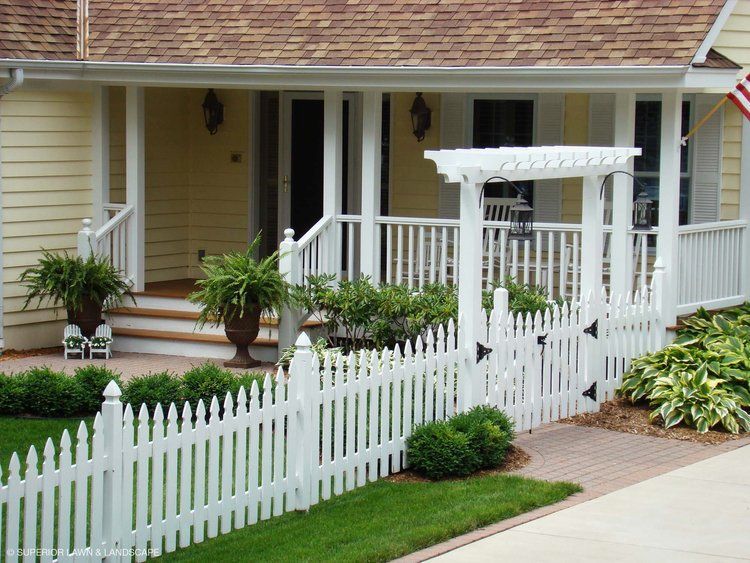 A white picket fence surrounds a house with a porch