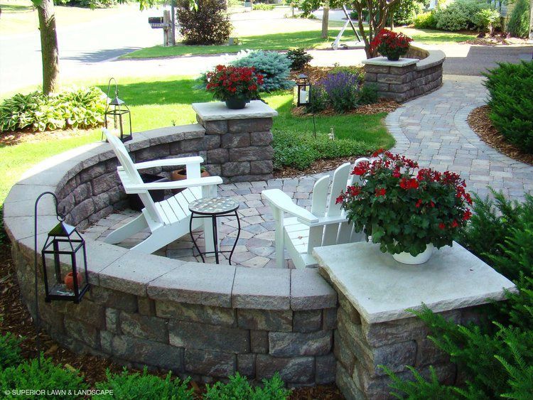 A patio with two chairs, a table, lanterns and flowers.