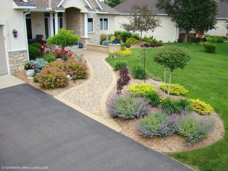 A house with a lush green lawn and a walkway leading to it