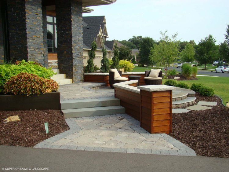 A patio with a wooden bench and chairs in front of a house