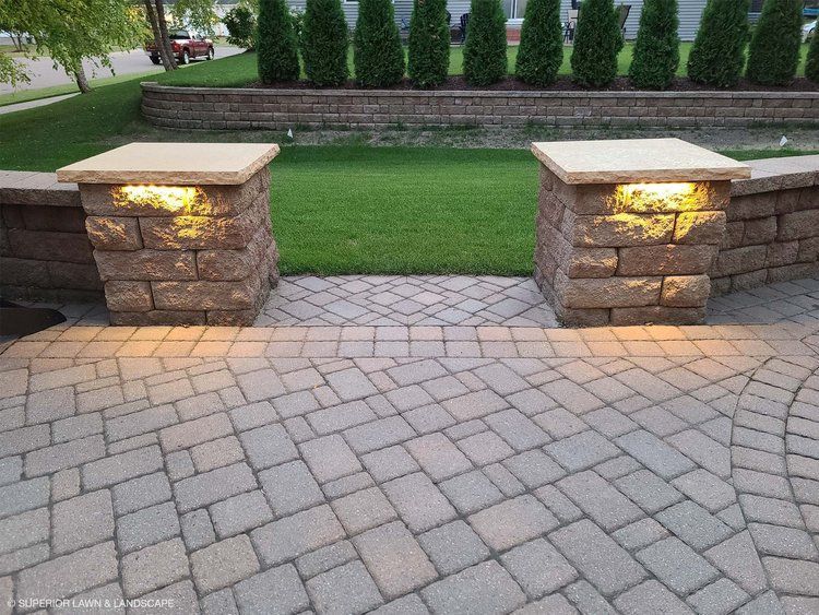 A brick walkway with pillars and lights on it