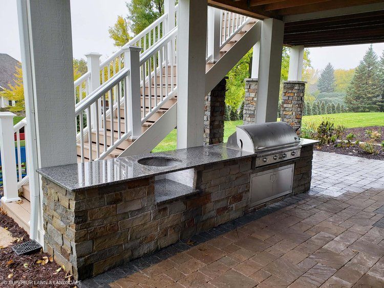 A patio with a grill and stairs in the background.