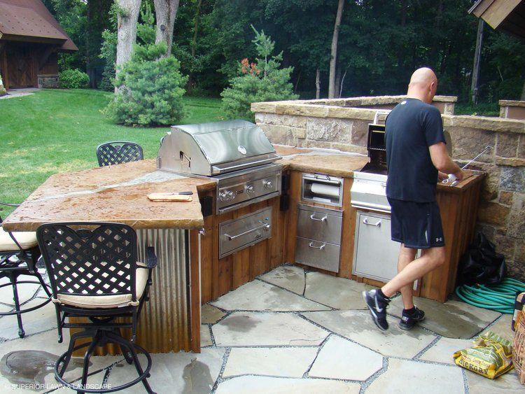 A man in a black shirt is standing in an outdoor kitchen