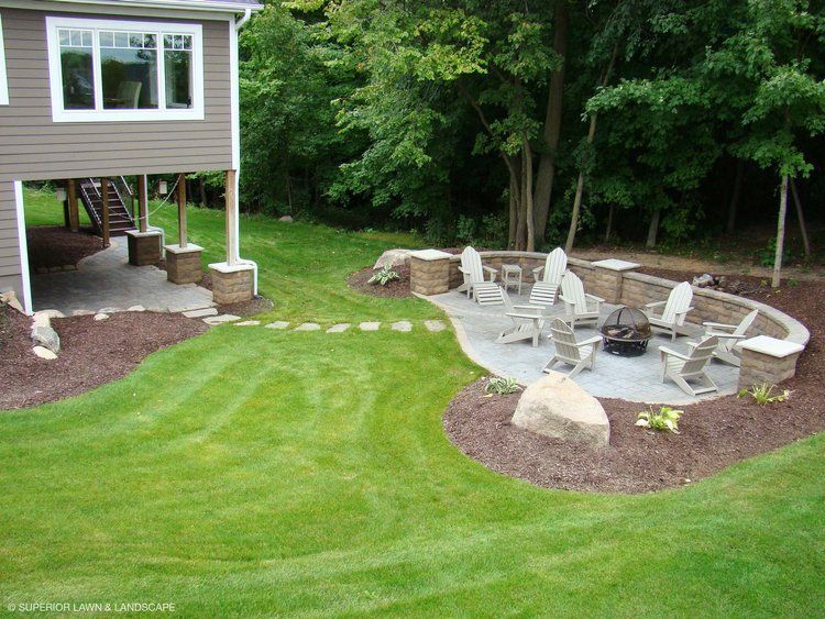 A patio with chairs and a fire pit in the backyard of a house.