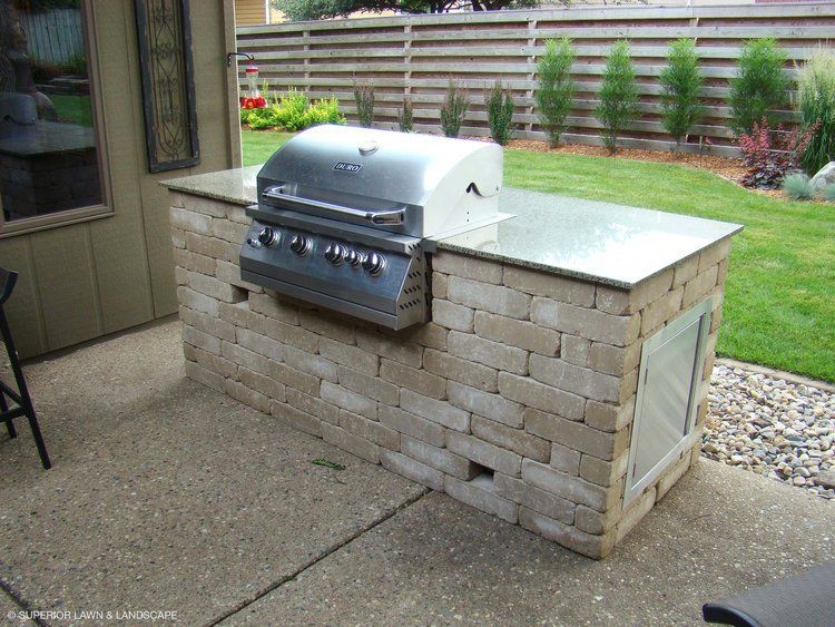 A grill is built into a brick wall on a patio