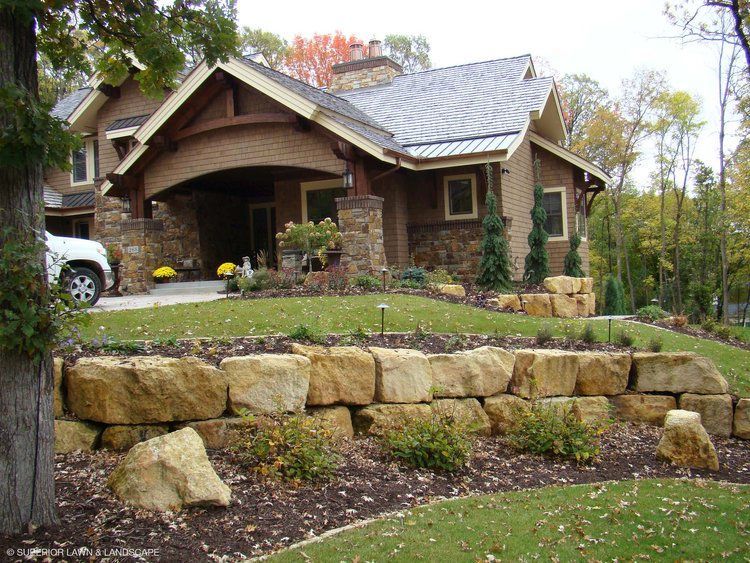 A large brick house with a stone wall in front of it