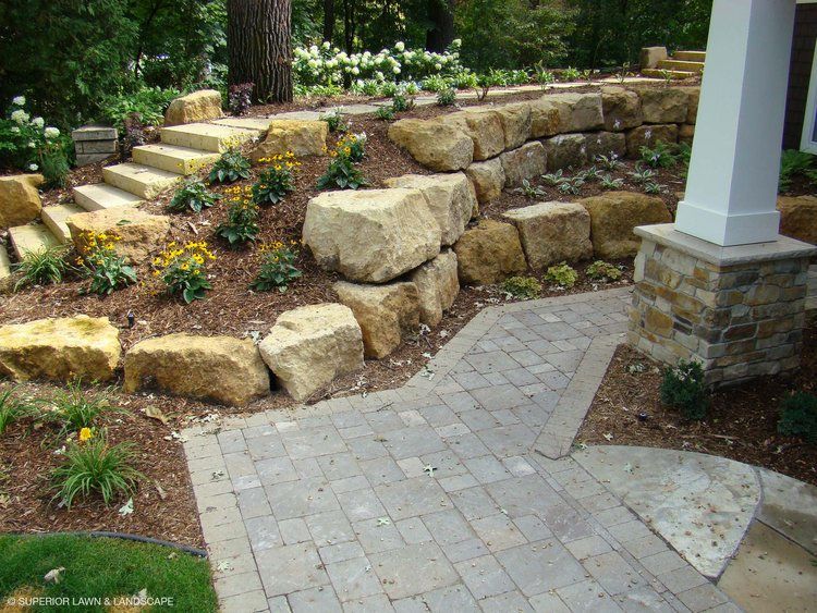 A brick walkway surrounded by large rocks and flowers