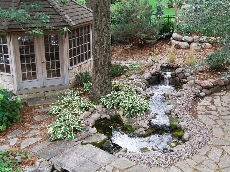 A pond with a waterfall and a gazebo in the background