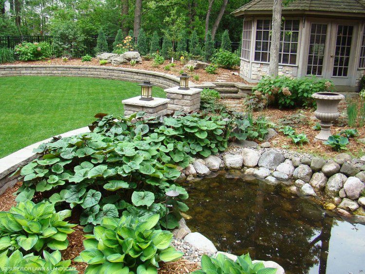 A garden with a pond and a gazebo in the background