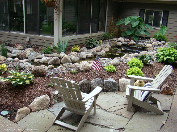 Two chairs are sitting on a stone patio in front of a house